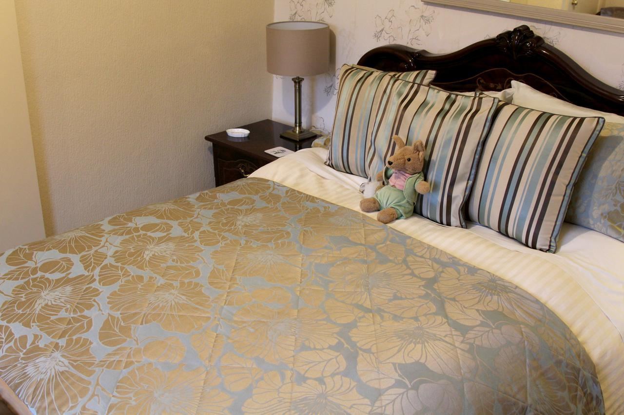 Double room with striped cushions and a Peter Rabbit toy at Kays Cottage